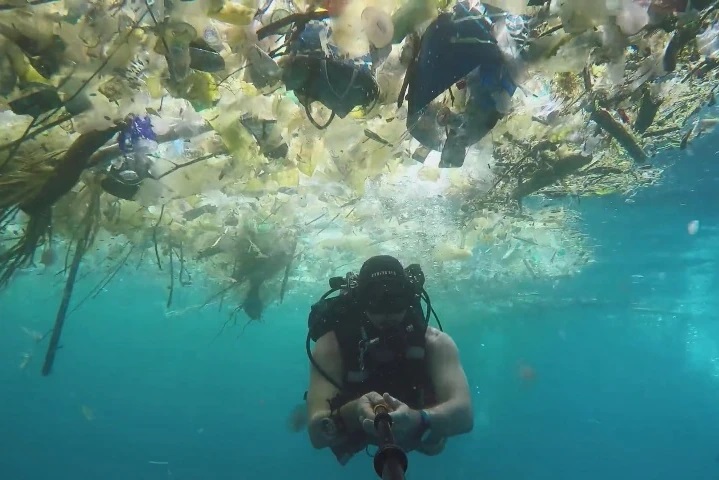 buzo rodeado de basura en el mar